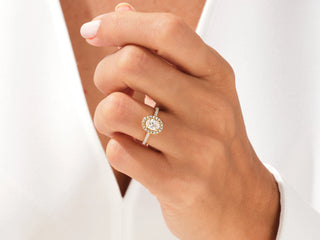 Oval-shaped moissanite engagement ring with halo of pavé-set diamonds and elegant band.