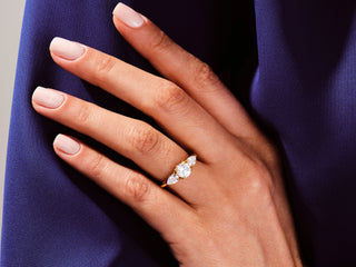 Round Moissanite Diamond Three-Stone Engagement Ring with pear-shaped side stones for timeless elegance.